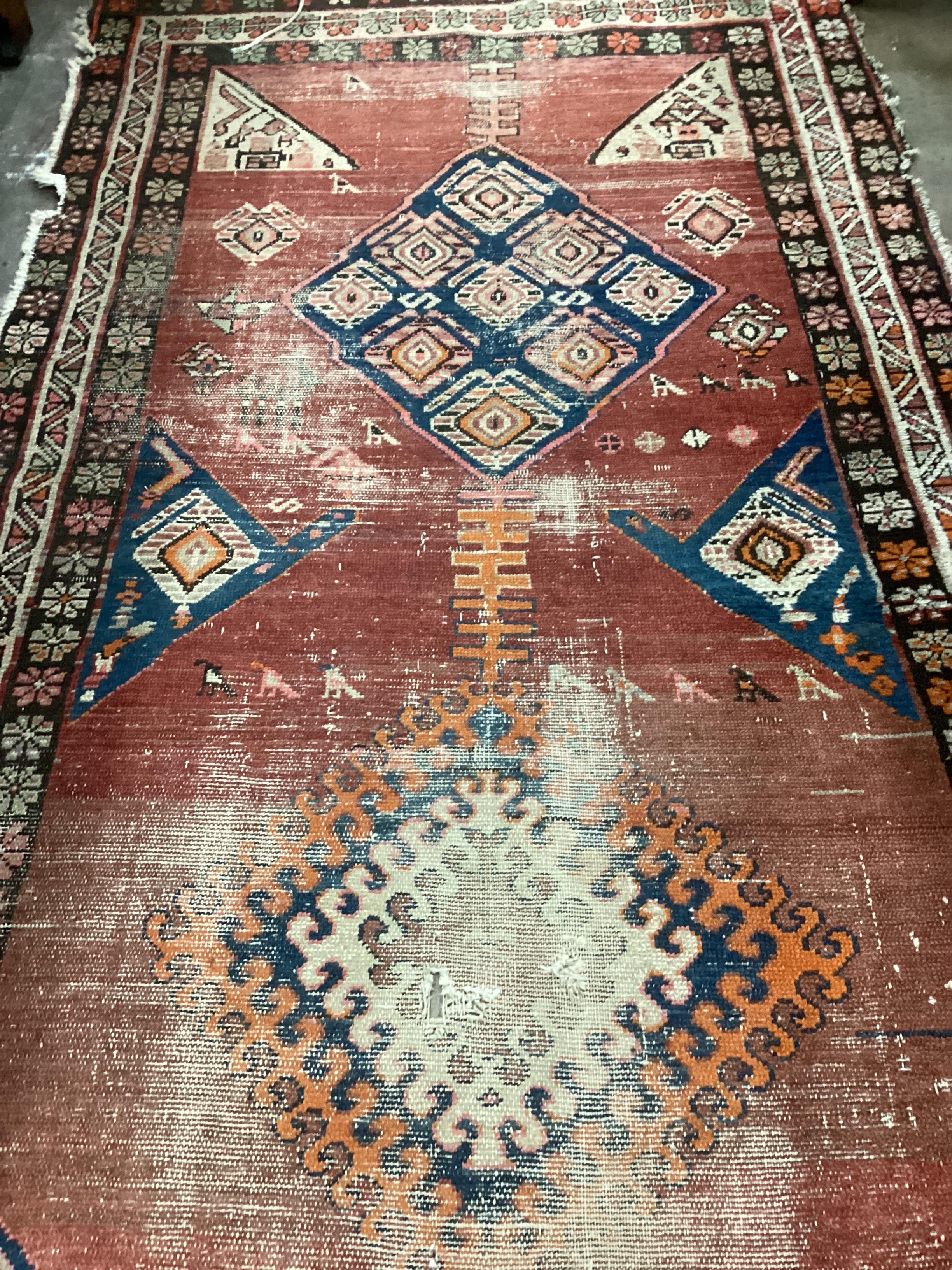 An Antique Caucasian brick red ground runner 336cm x 110cm, severely worn and holed
